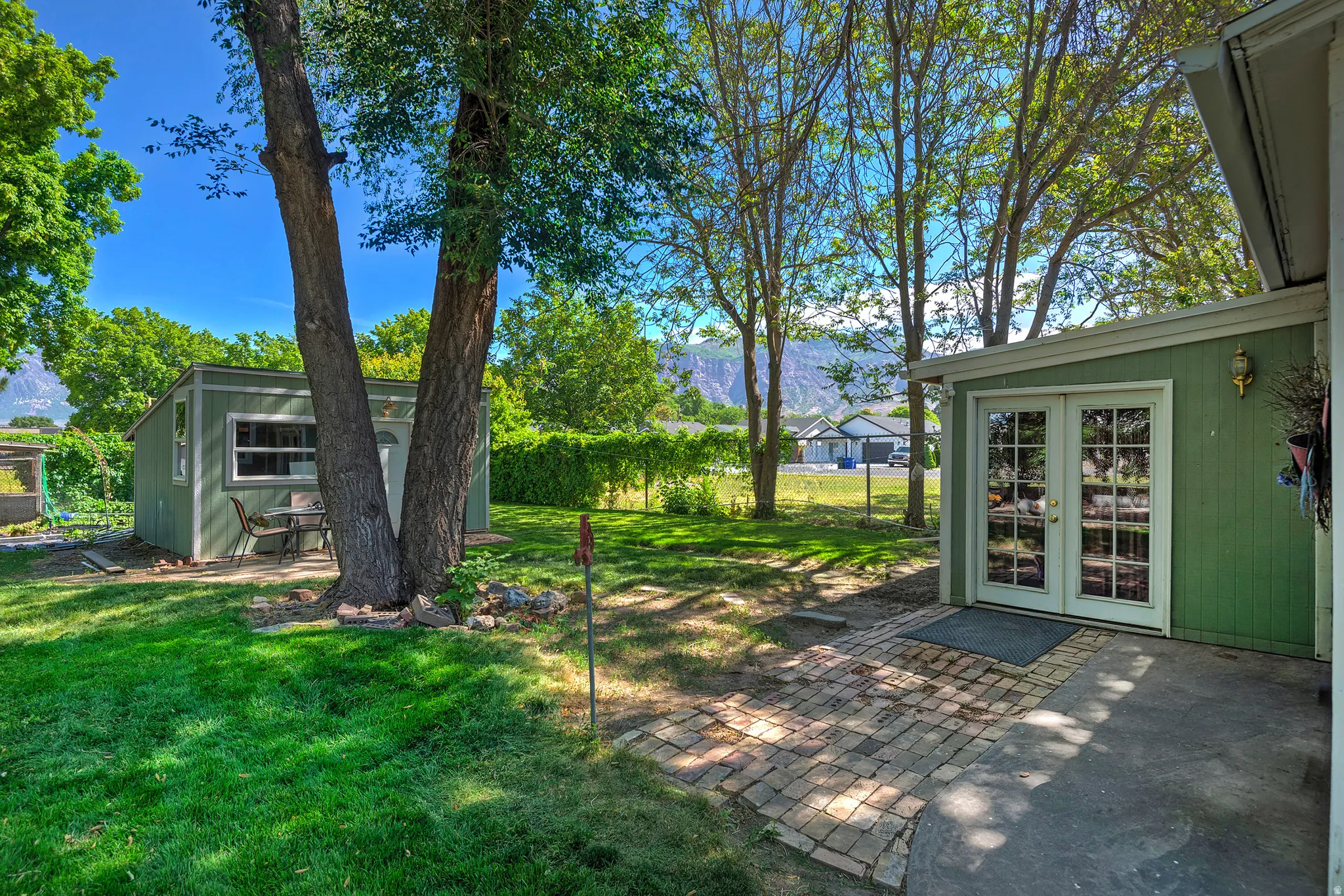 Expansive backyard featuring a green lawn, mature trees, and a mountain backdrop
