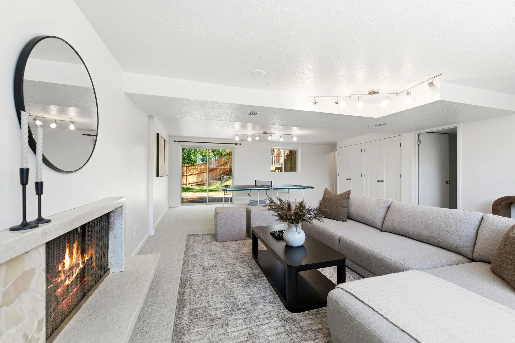 Spacious living area featuring a modern linear fireplace with a stone surround, recessed lighting, and track lighting