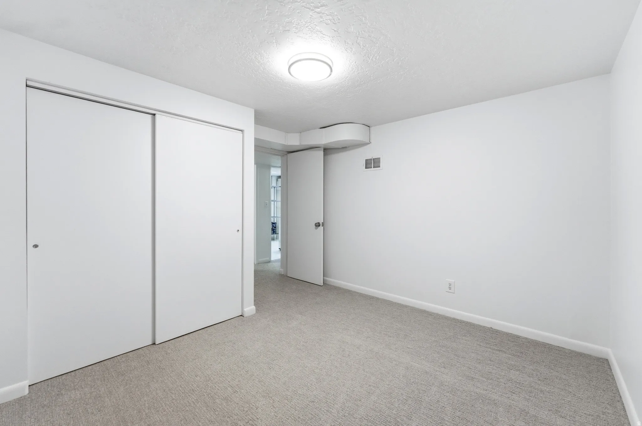 Carpeted interior room featuring white walls, white baseboards, and a flush mount ceiling light fixture