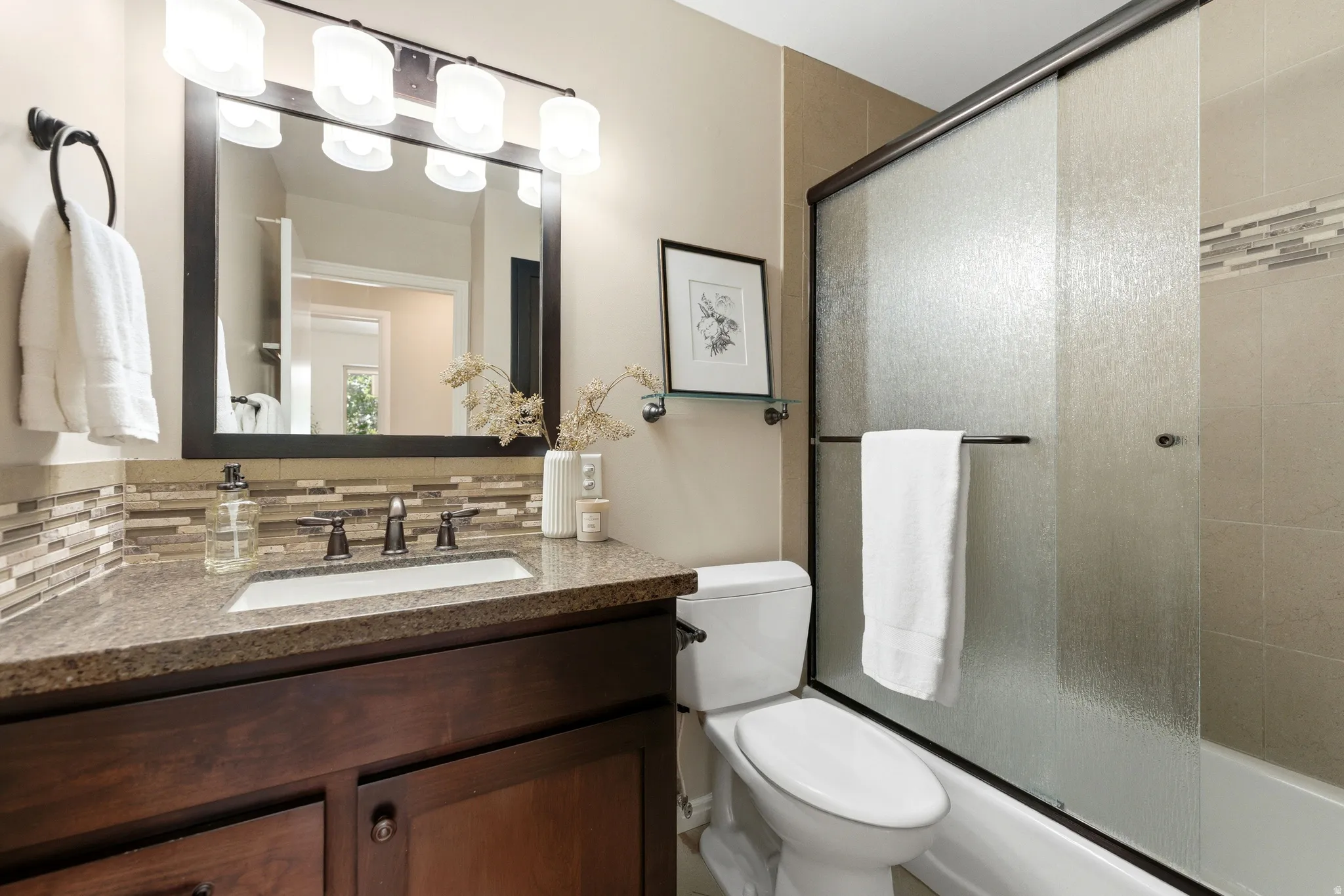 Vanity with a granite-style countertop, undermount sink, and dark wood cabinetry