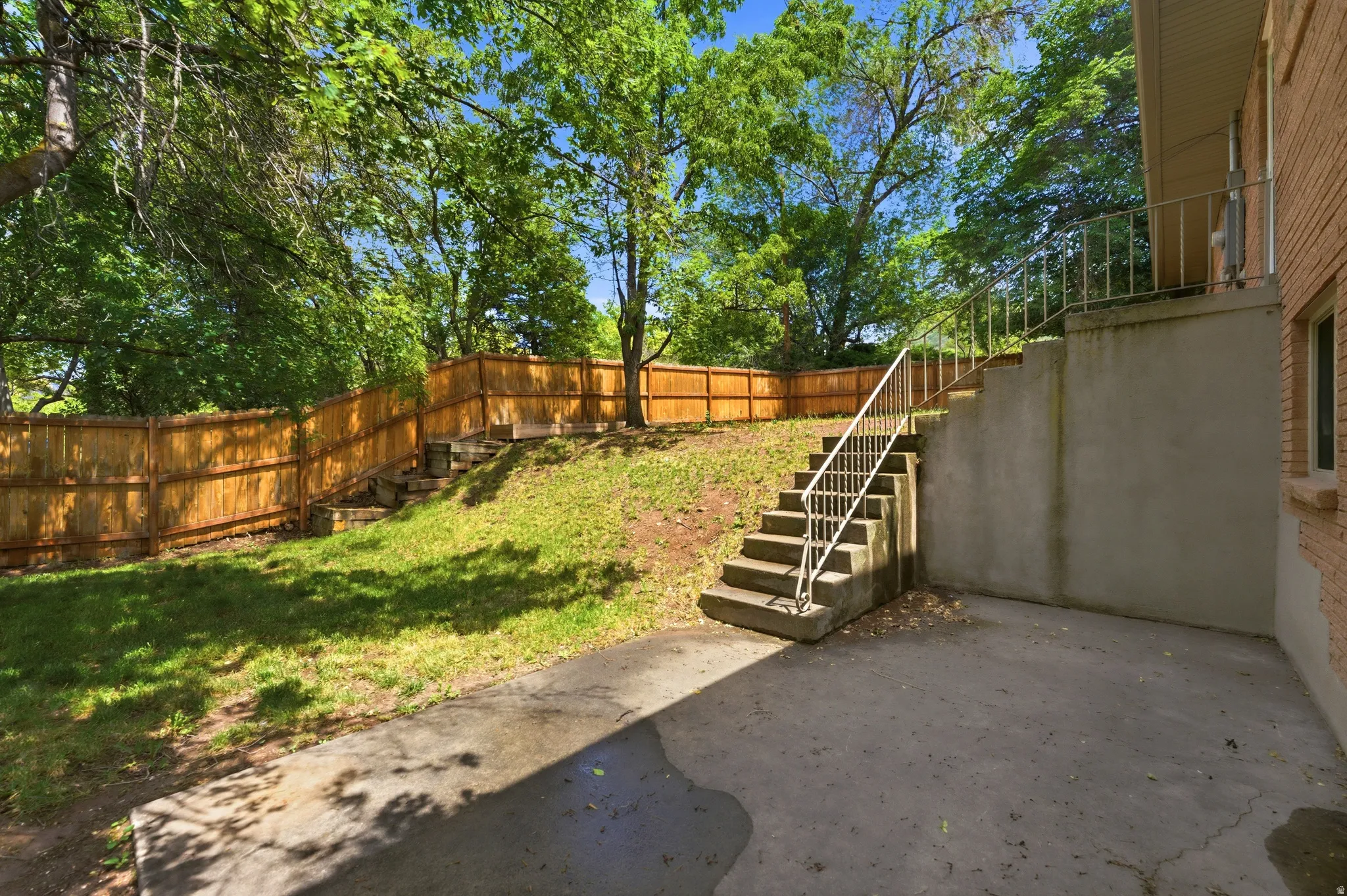 Exterior concrete patio with direct access to a concrete staircase featuring metal railings