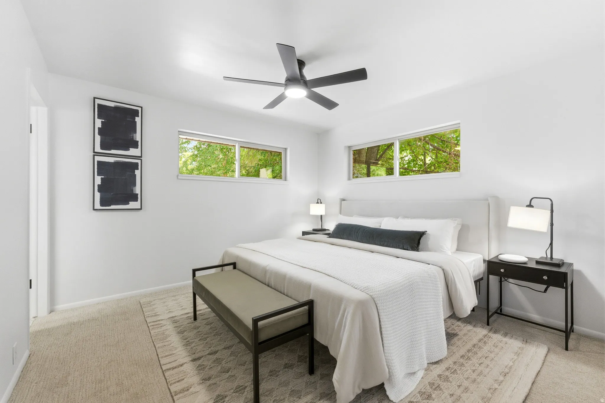 Bright bedroom featuring two transom windows, a ceiling fan, and light-colored carpeting