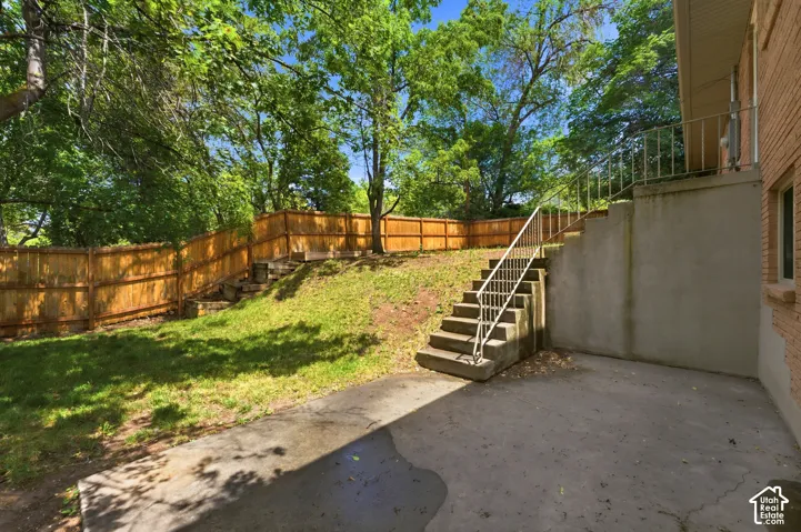 Exterior concrete patio with direct access to a concrete staircase featuring metal railings