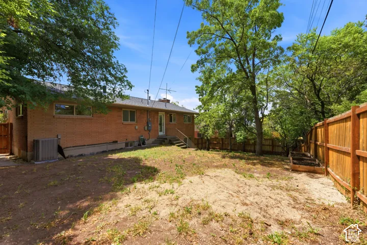 Expansive rear yard featuring a brick-clad home exterior, mature trees, and a wood fence