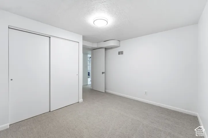 Carpeted interior room featuring white walls, white baseboards, and a flush mount ceiling light fixture