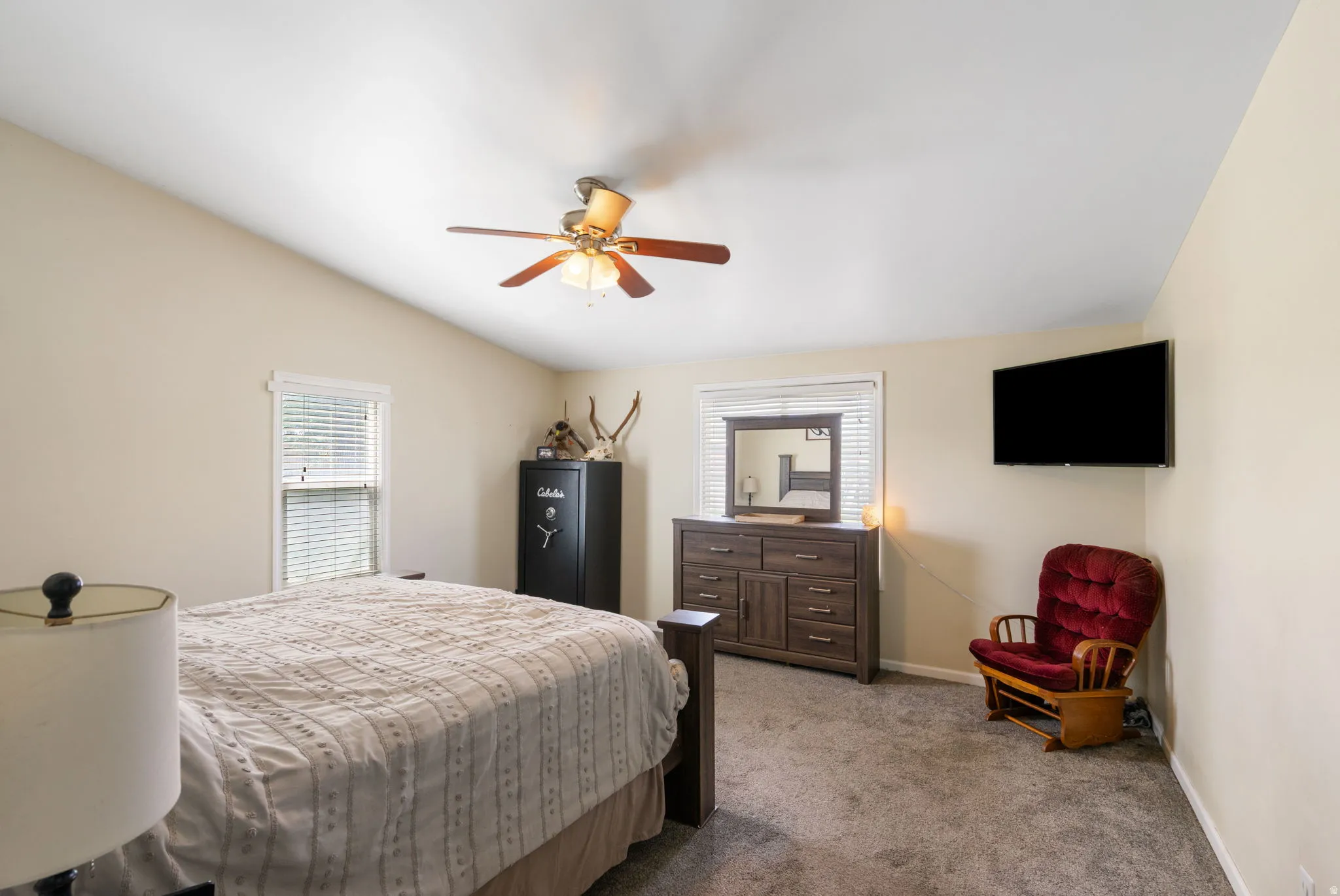Spacious bedroom featuring vaulted ceilings, a ceiling fan, and carpeted flooring
