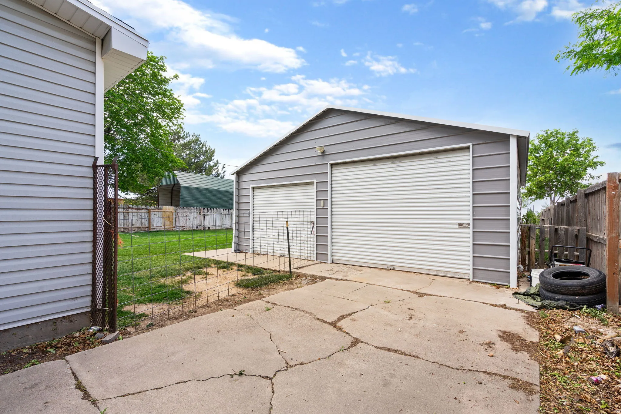 Detached two-car garage featuring grey metal siding and two white roll-up garage doors