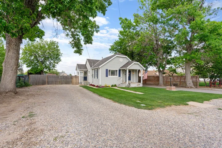 Single-story residence featuring light gray siding, dark blue shutters, a covered front porch, and a gravel driveway