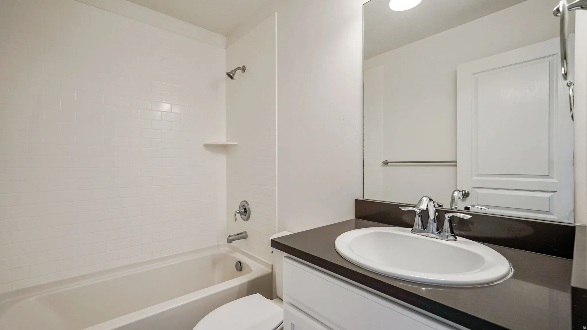 Bathroom vanity featuring a dark countertop, white oval undermount sink, and chrome fixtures