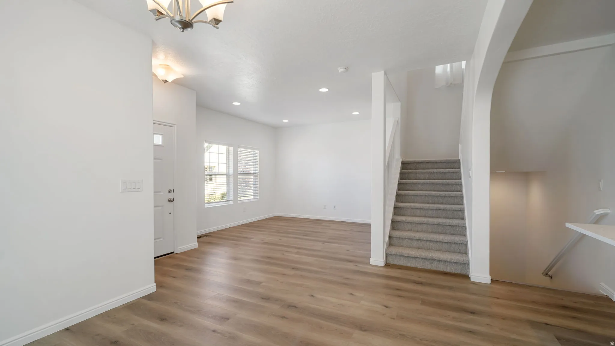 Open-concept living space with wood-finish flooring, recessed lighting, and a neutral color palette
