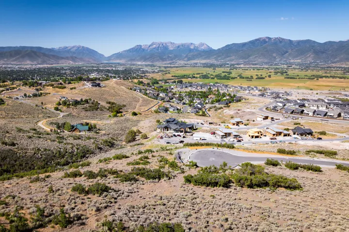 Expansive valley landscape featuring a winding road network, distant mountain range, and scattered residential properties