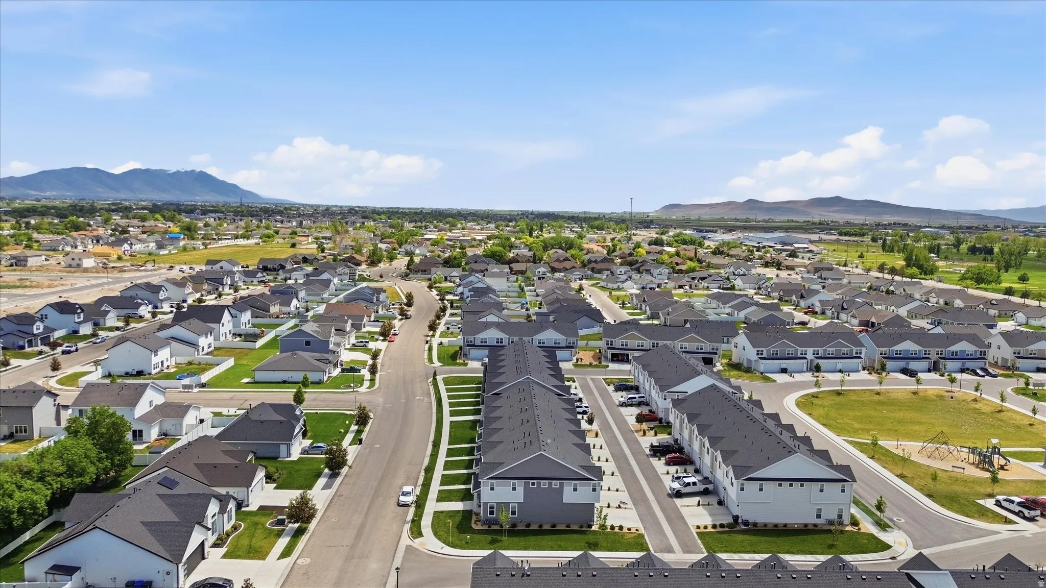 Expansive residential development featuring a variety of housing types, broad paved streets, and a clear mountain backdrop