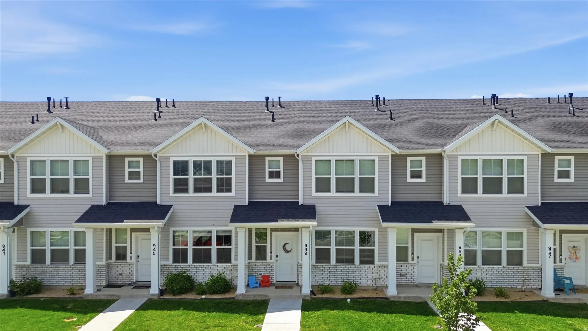 Townhome exterior featuring light gray siding, white trim, dark gray shingle roofing, and a prominent front-facing gable