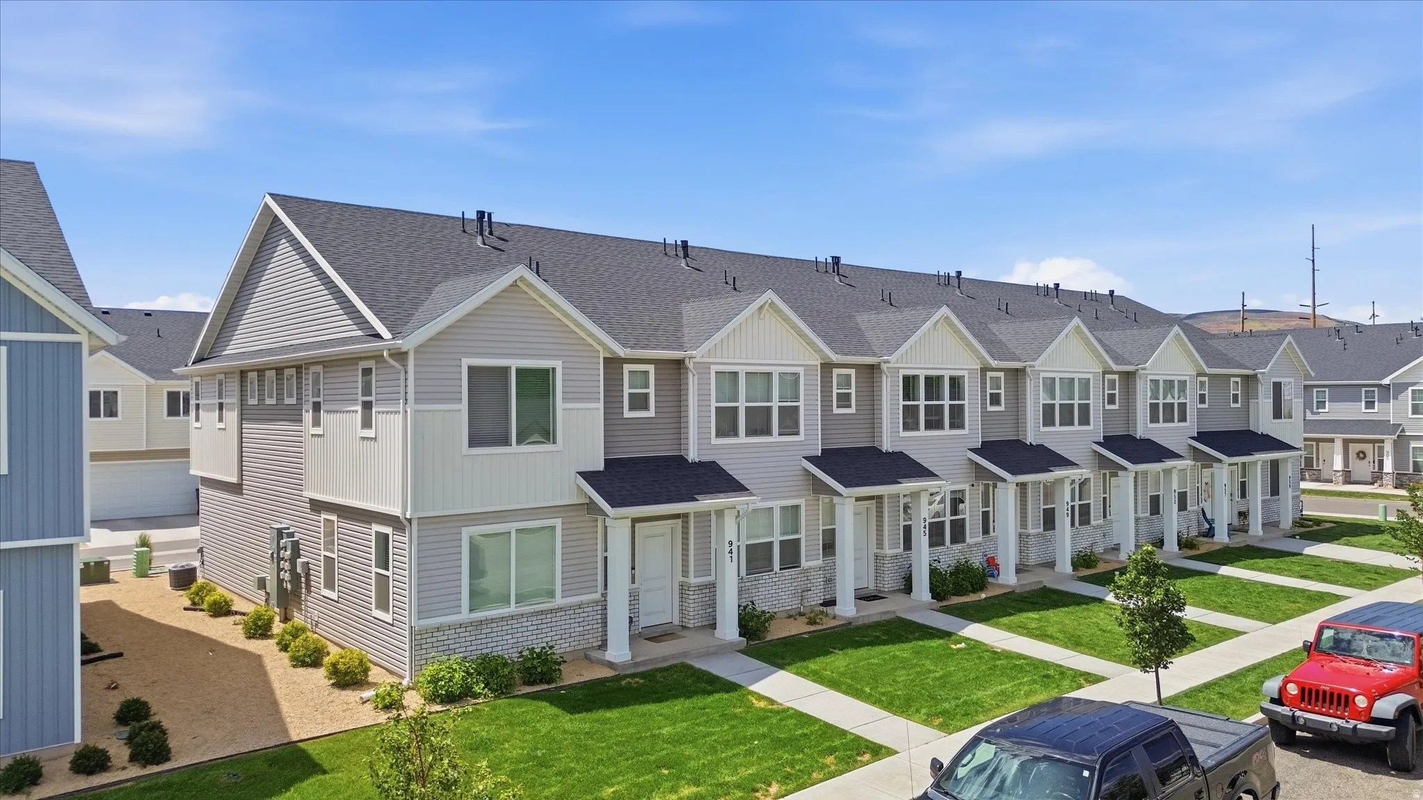 Newly constructed townhome community featuring a uniform aesthetic of gray siding with white trim and dark asphalt shingle roofs