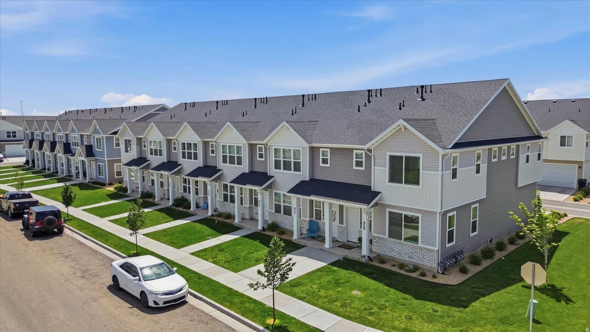 Modern townhome exterior featuring gray siding, white trim, and dark shingle roofing