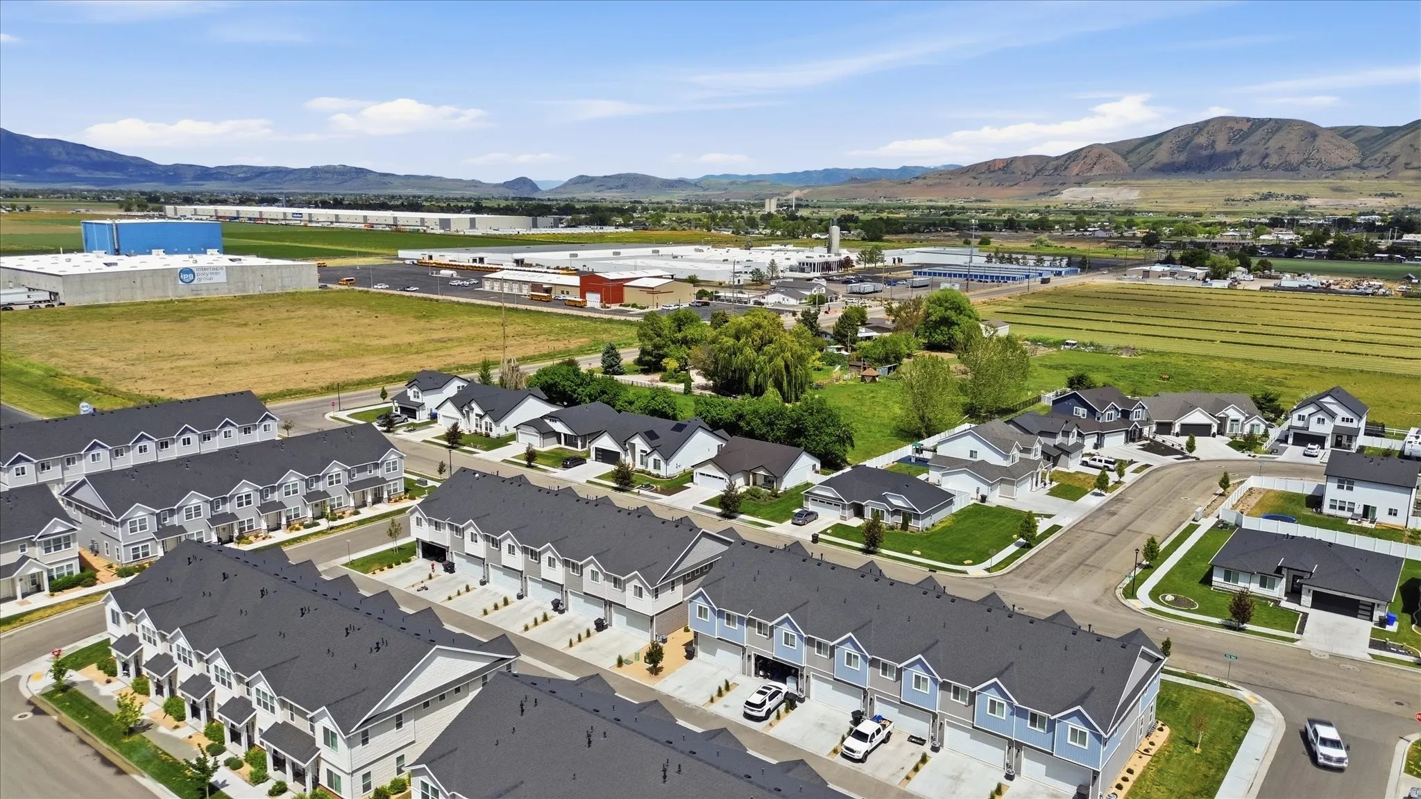 Aerial perspective highlighting multiple residential properties with dark-shingled roofs, light-colored exteriors, and attached garages