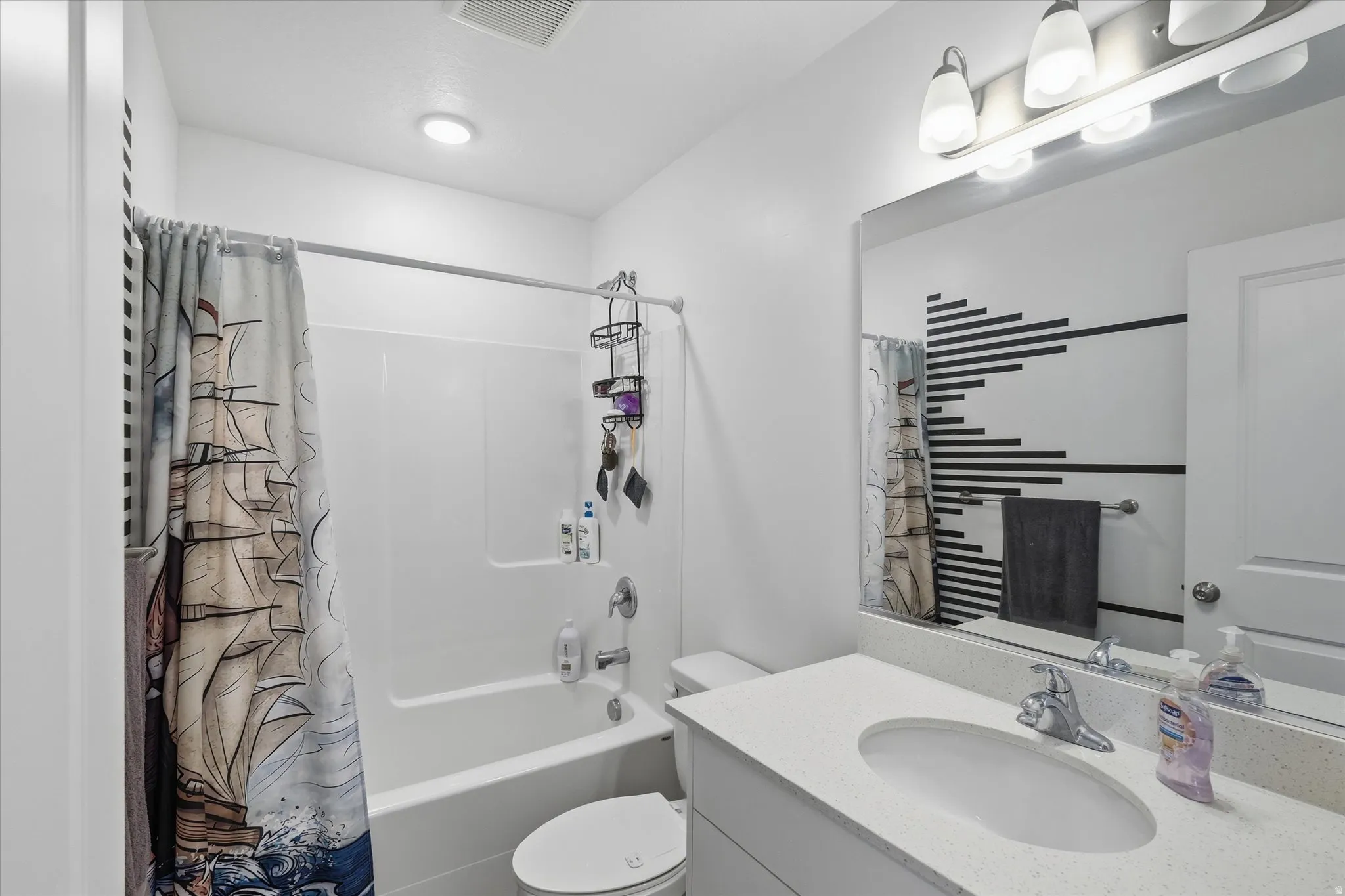 Bathroom featuring a white vanity with a light-colored countertop, an oval undermount sink, and a chrome faucet