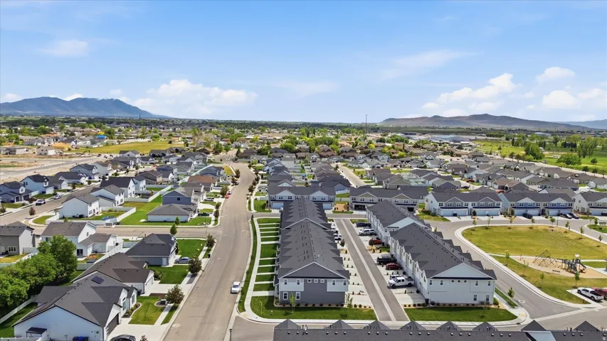 Expansive residential development featuring a variety of housing types, broad paved streets, and a clear mountain backdrop