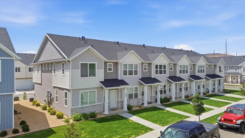 Newly constructed townhome community featuring a uniform aesthetic of gray siding with white trim and dark asphalt shingle roofs