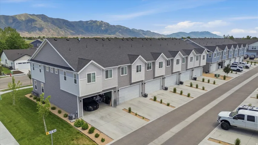 Contemporary townhome exterior featuring multi-toned siding, attached garages with concrete driveways, and a row of similar architectural styles