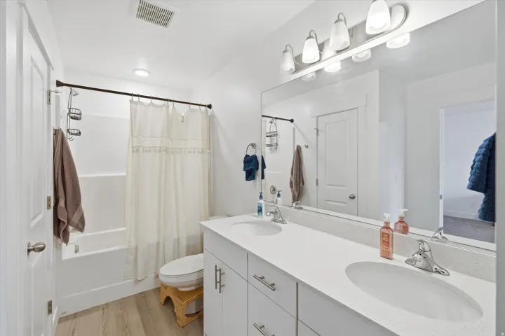 Bathroom featuring a dual vanity with undermount sinks, a white countertop, and chrome fixtures