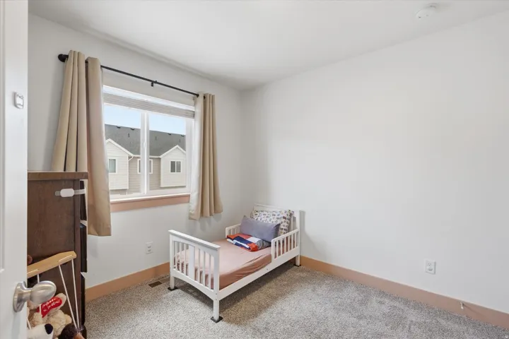 Spacious room featuring light gray carpet, white walls, and a large window with natural wood trim