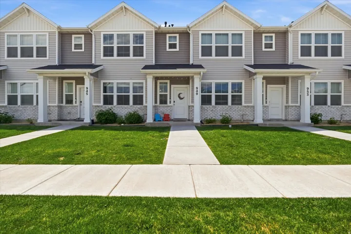 Modern townhome exterior featuring light-toned siding, white trim accents, and a covered front porch