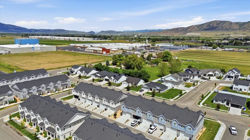 Aerial perspective highlighting multiple residential properties with dark-shingled roofs, light-colored exteriors, and attached garages