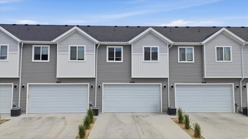 Contemporary townhome exterior featuring gray siding, white accents, a dark shingle roof, and an attached two-car garage