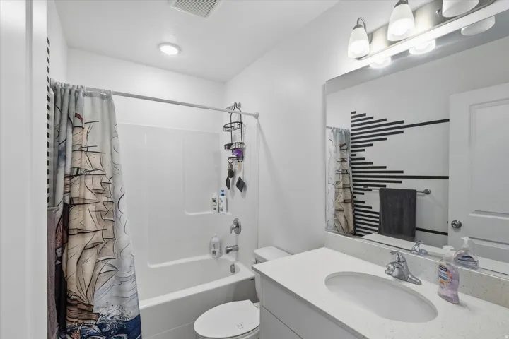 Bathroom featuring a white vanity with a light-colored countertop, an oval undermount sink, and a chrome faucet
