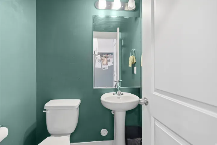Pedestal sink with chrome fixtures, framed mirror, and three-light vanity bar