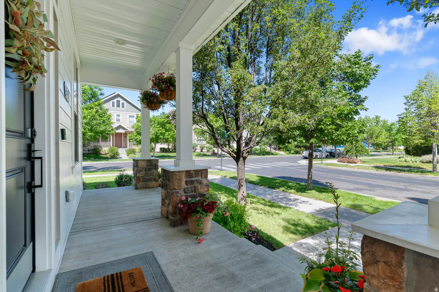 Inviting covered front porch with stone-wrapped columns and a concrete floor