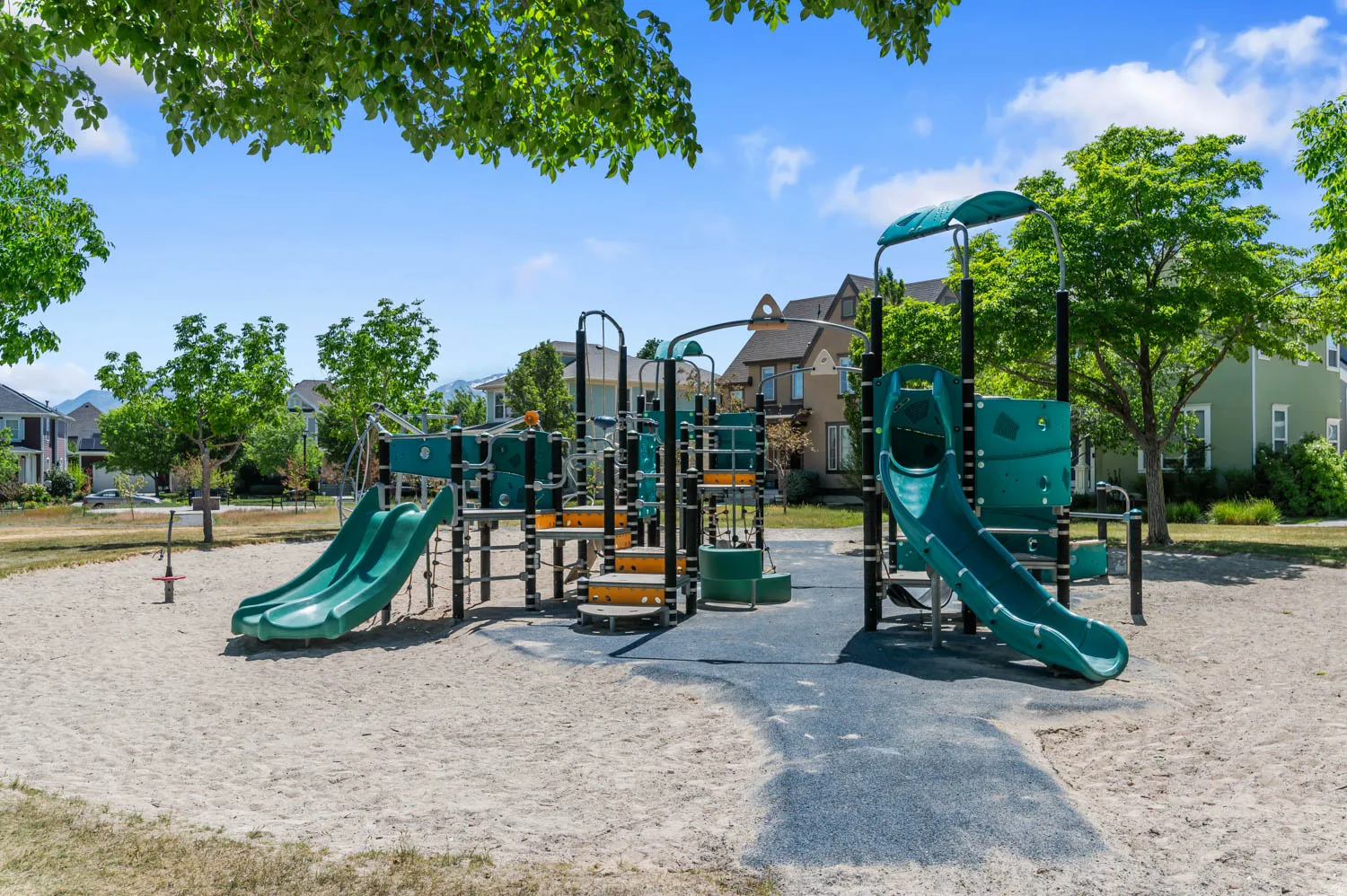 Community playground featuring multiple slides, climbing structures, and sand ground cover