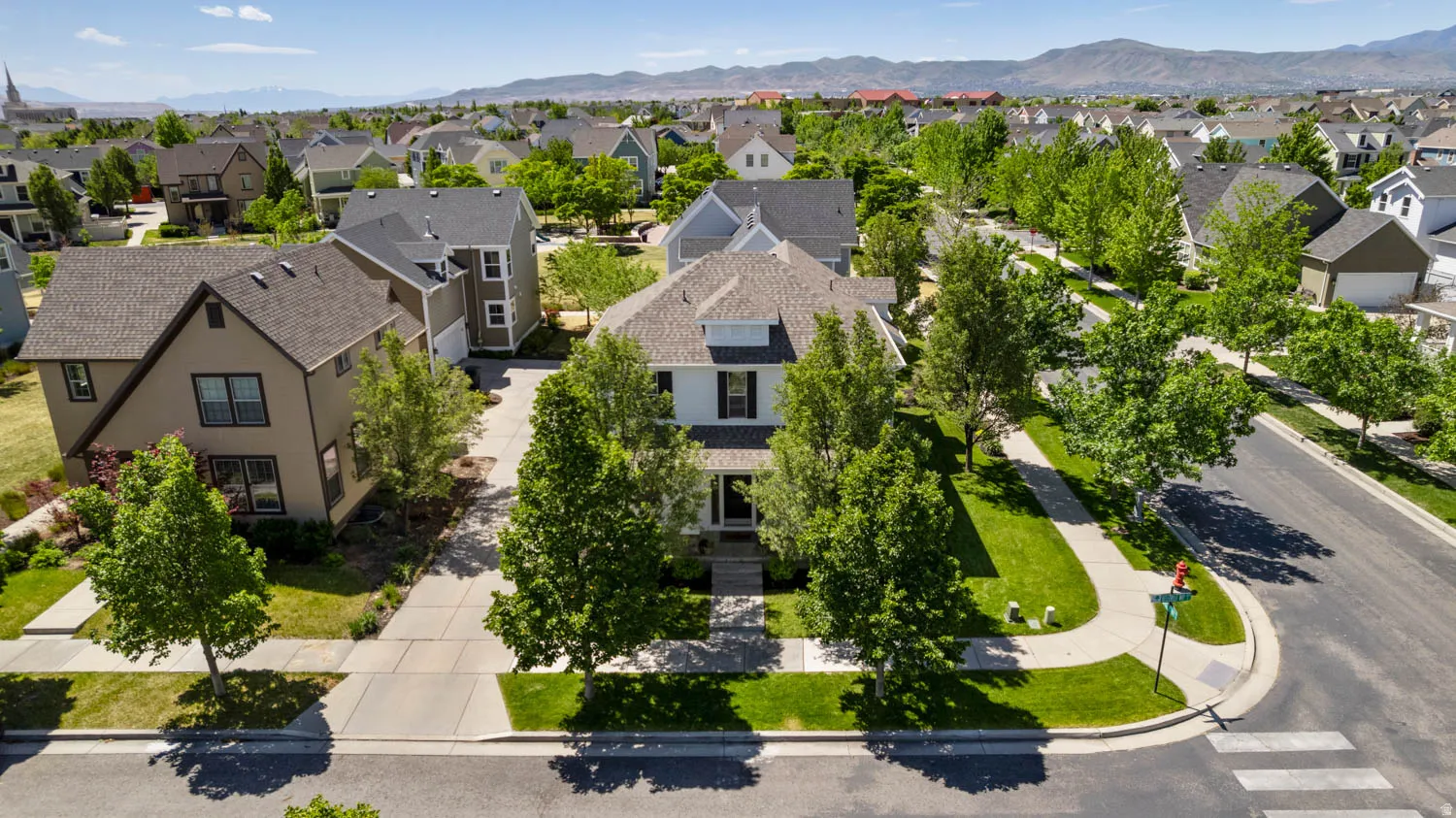 Corner lot residence featuring a crisp white exterior, dark roof, and multiple dormer windows