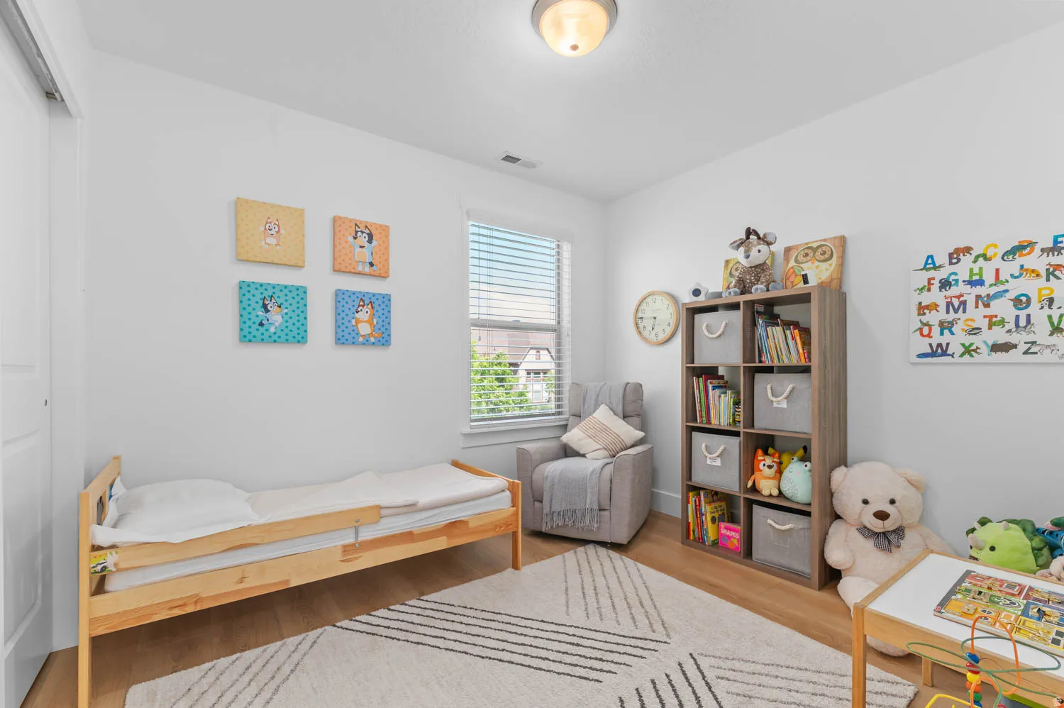 Light-filled room featuring wood-finish flooring, a window with horizontal blinds, and a built-in closet with a white panel door