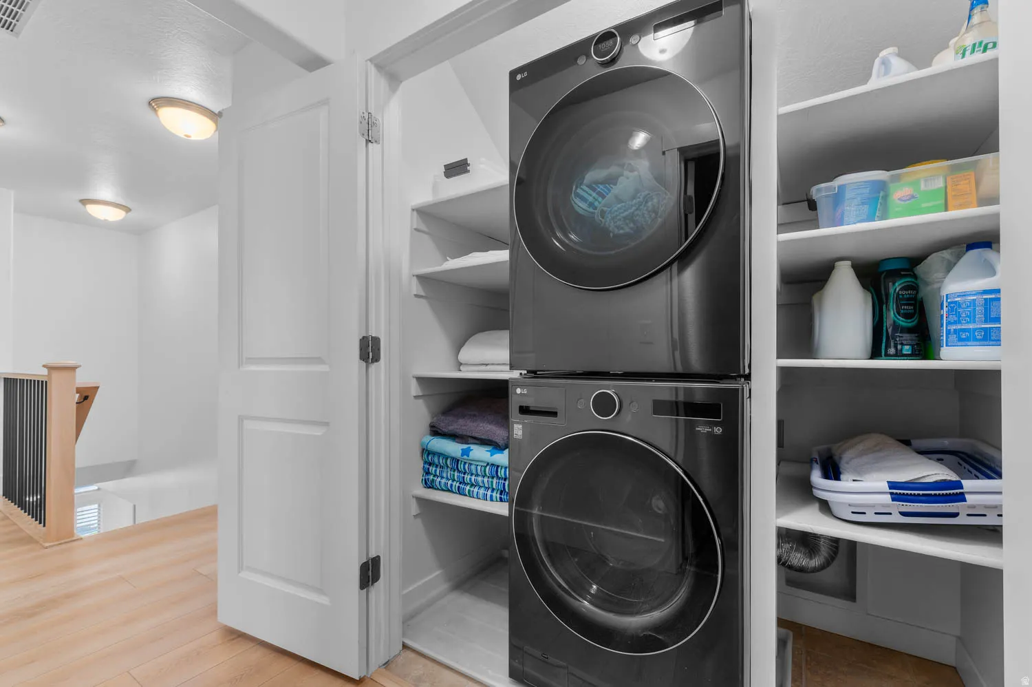 Dedicated laundry closet featuring a stacked washer and dryer, integrated shelving, and a durable tile floor