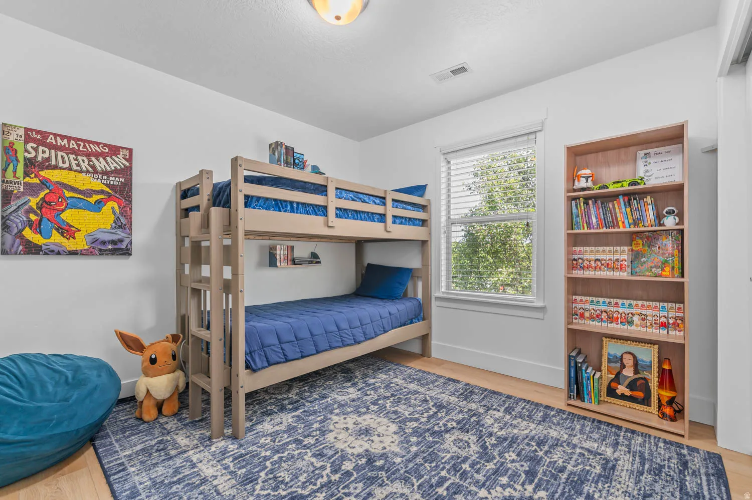 Bright room featuring light wood-finish flooring and a large window with blinds