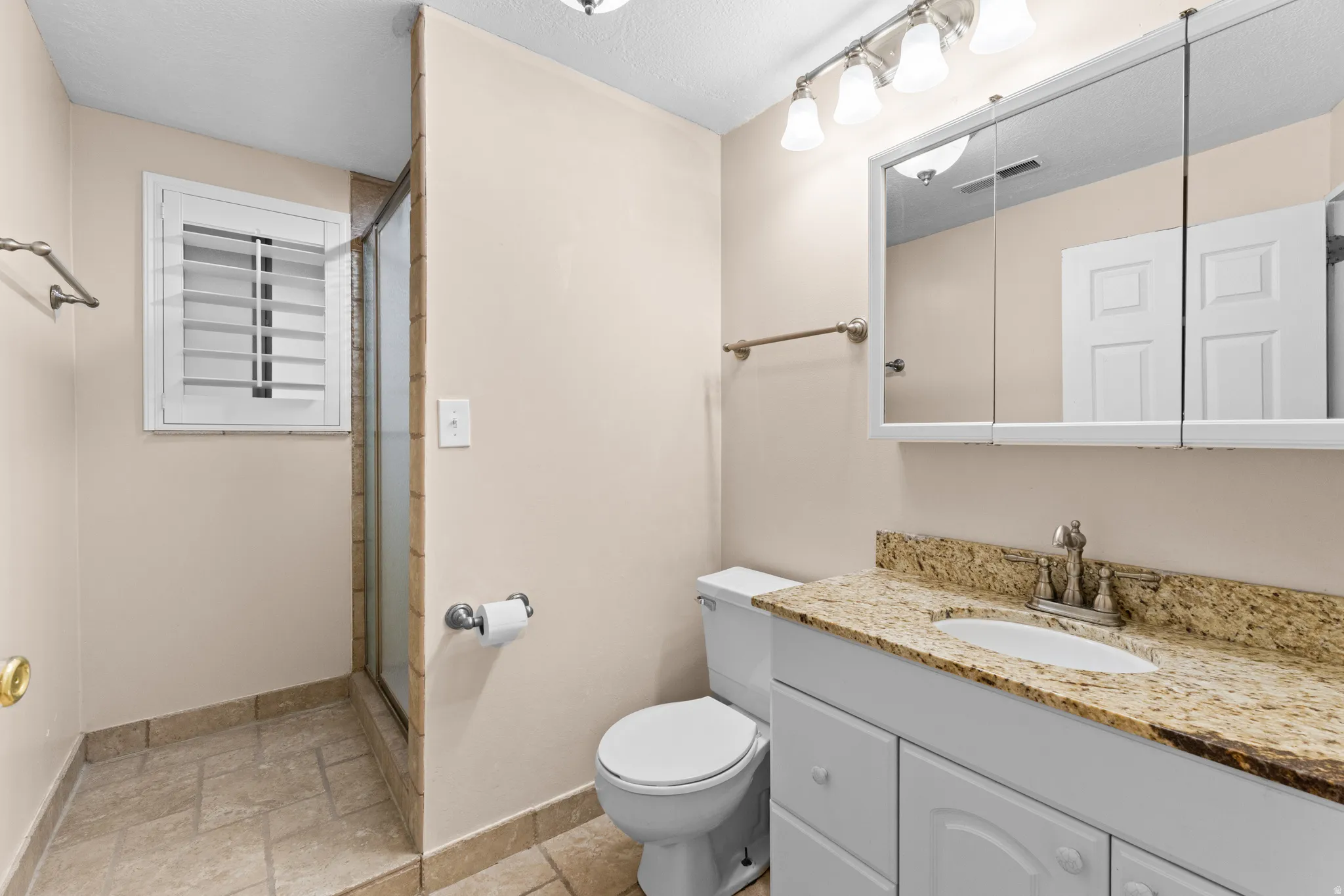Bathroom featuring a vanity with a stone countertop, an integrated sink, and a mirrored medicine cabinet