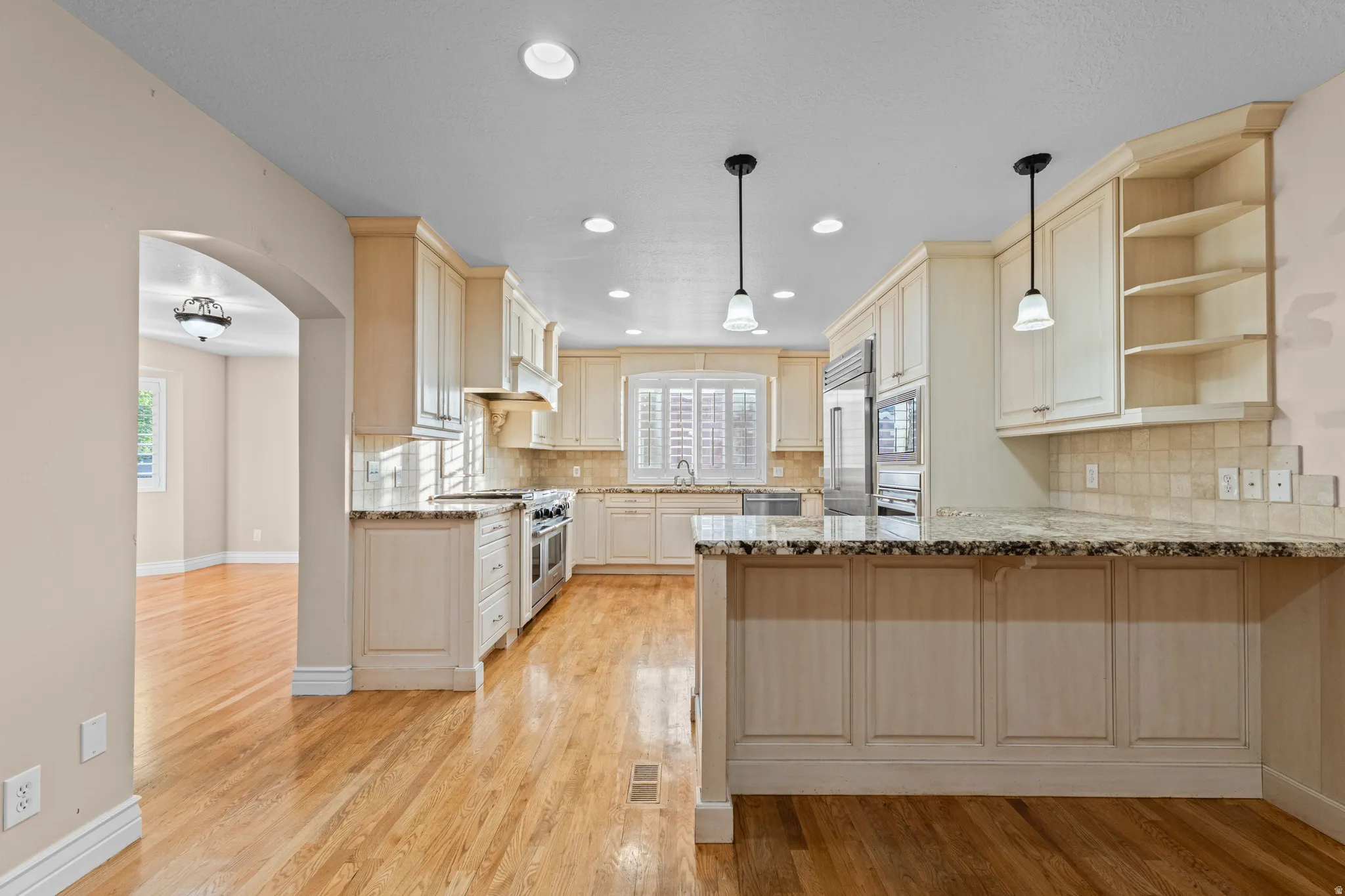 Kitchen featuring light-toned cabinetry, granite countertops, stainless steel appliances, recessed lighting, and wood-finish flooring