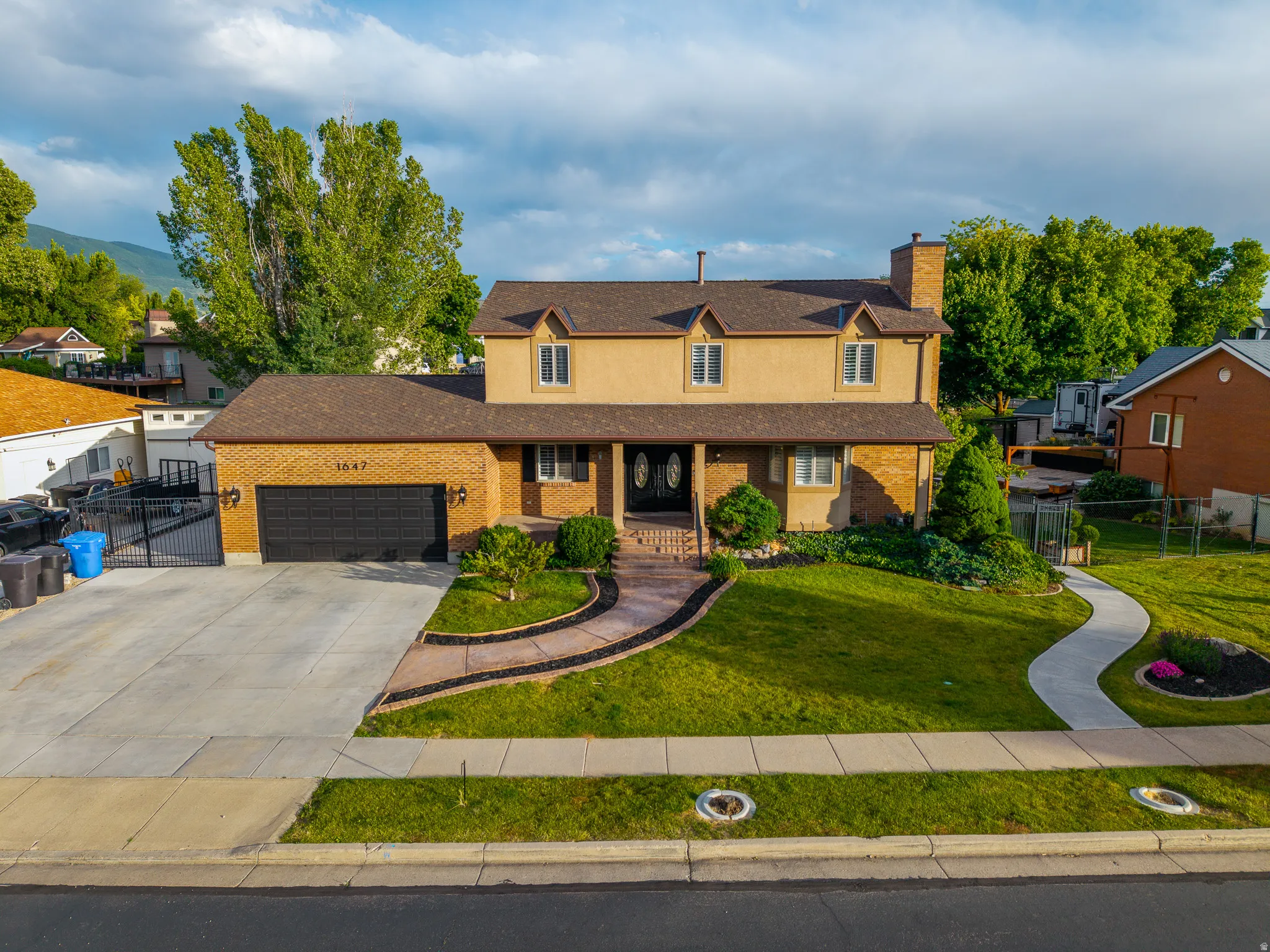 Traditional-style residence featuring a two-car garage with a dark door, a brick facade, and a covered entry