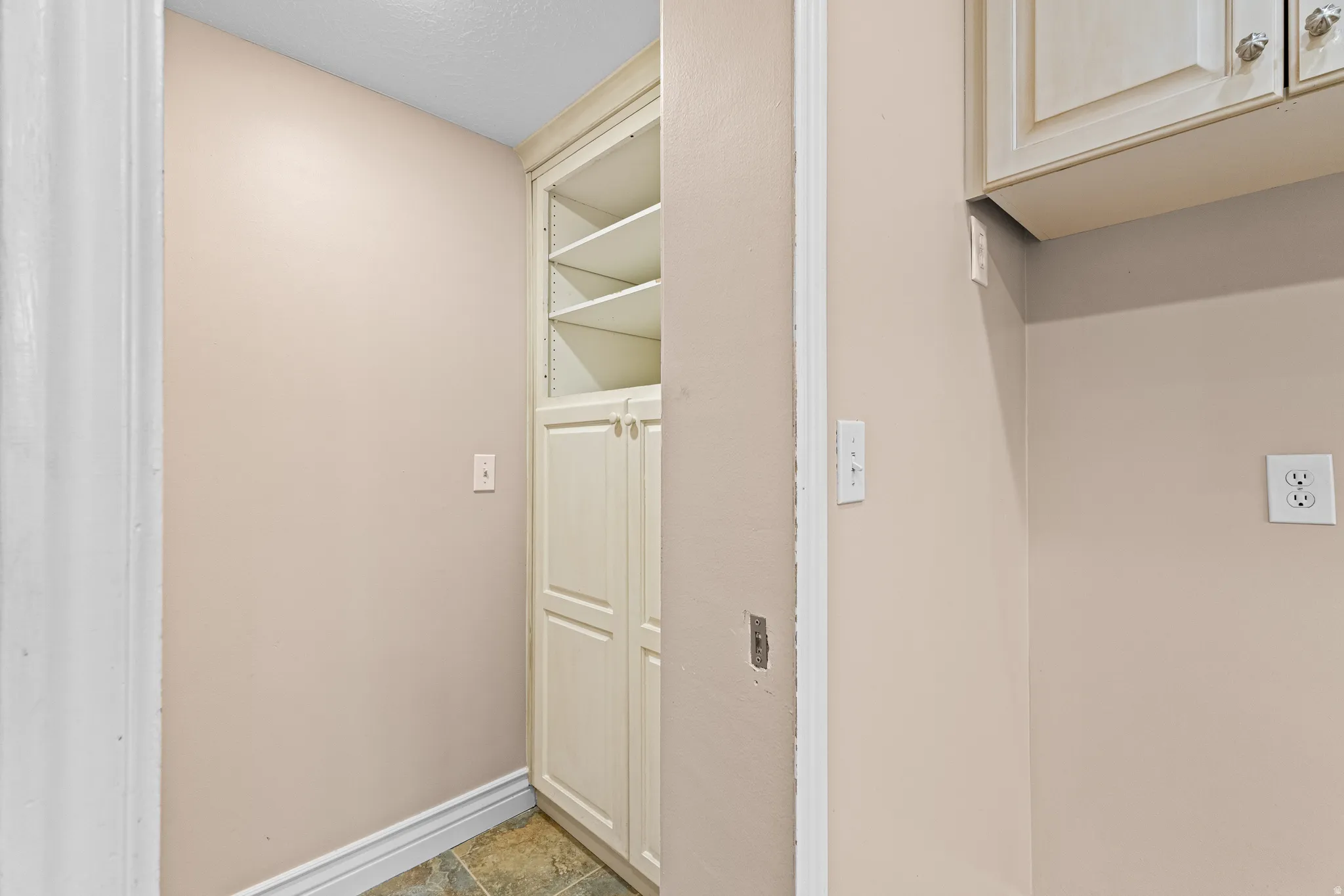 Built-in cabinetry featuring upper shelving and lower storage, complemented by multi-toned floor tiling