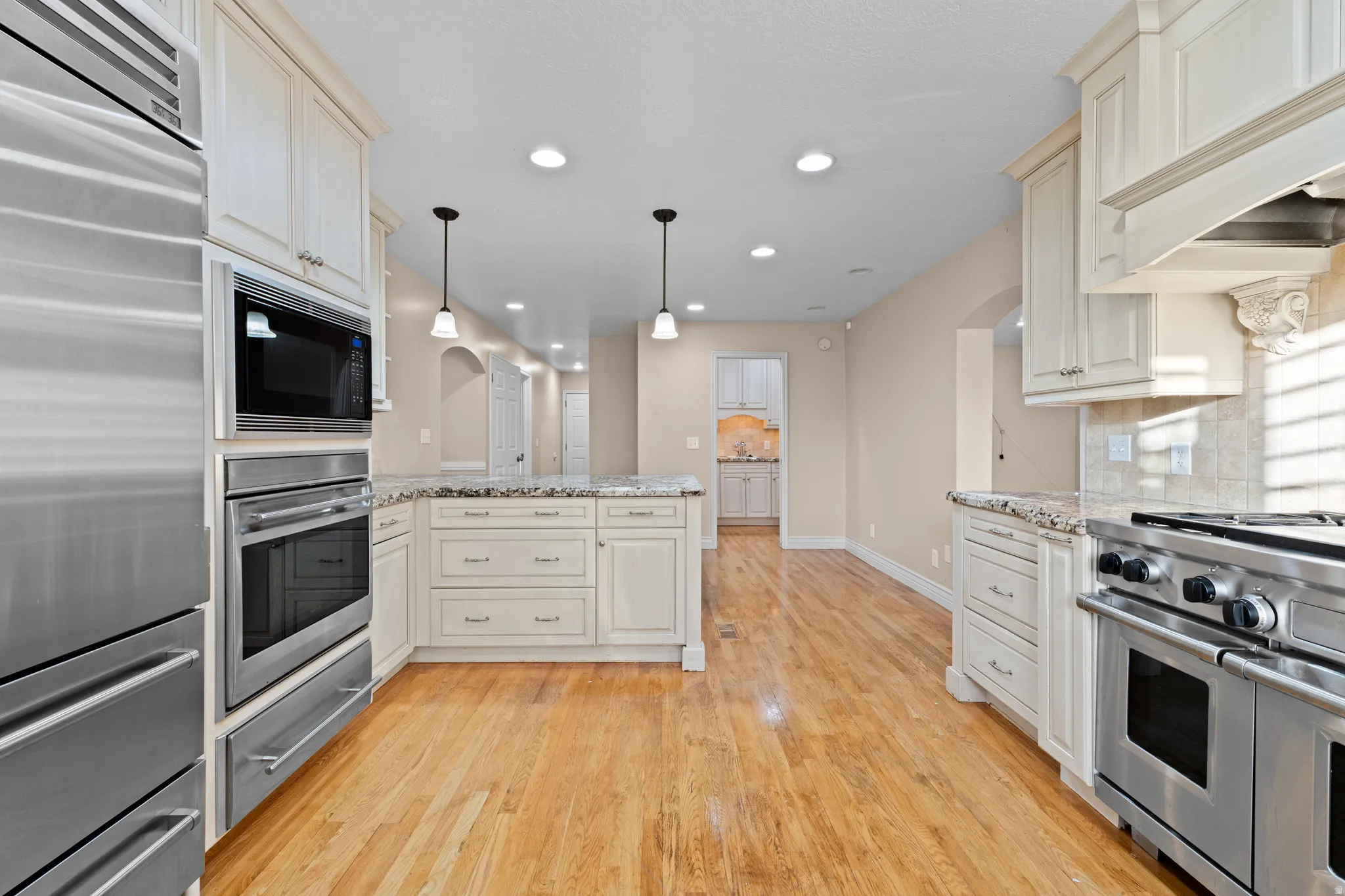 Gourmet kitchen featuring a built-in stainless steel refrigerator, double ovens, and a gas range