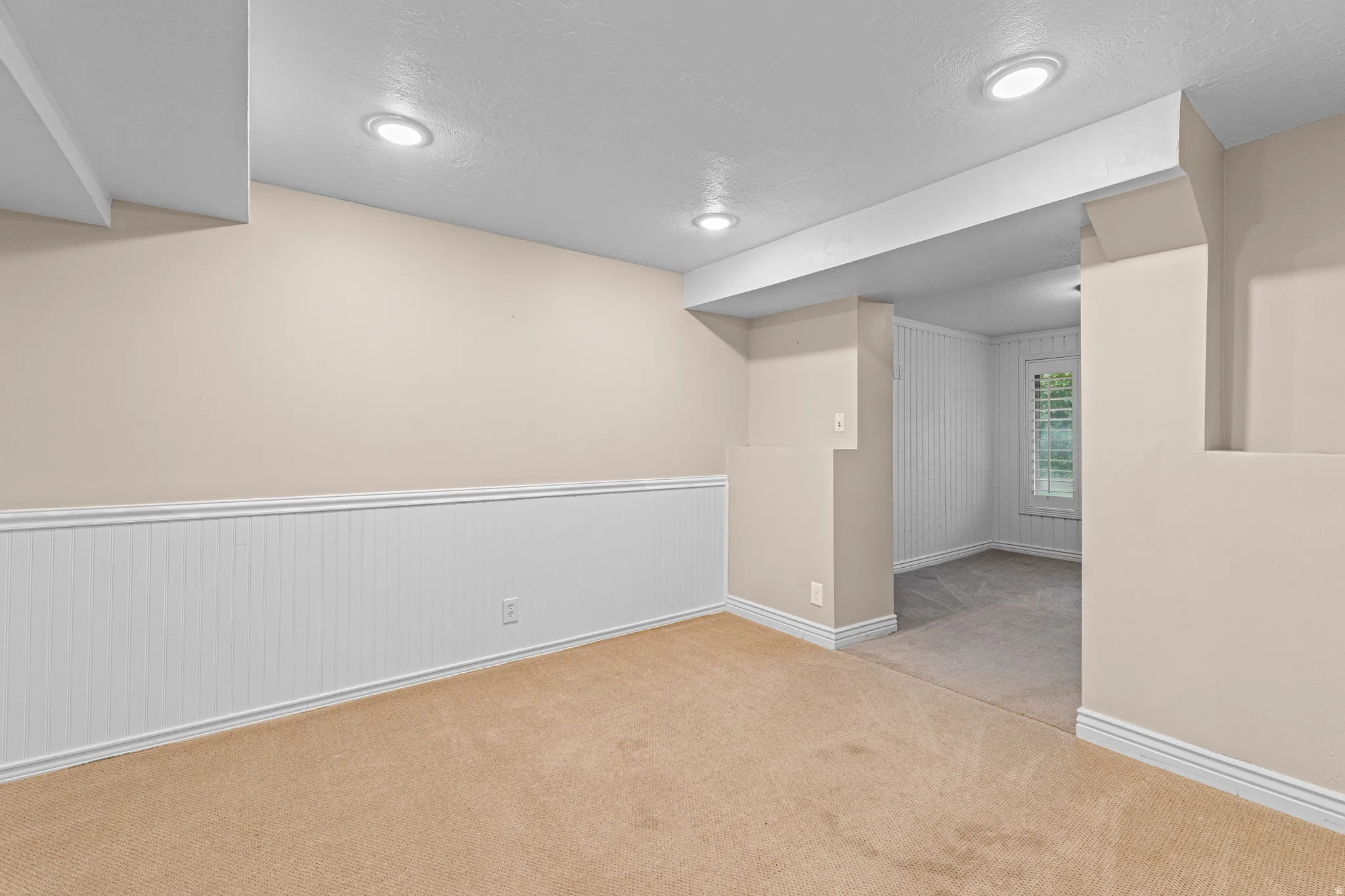 Carpeted room with recessed lighting and beadboard wainscoting