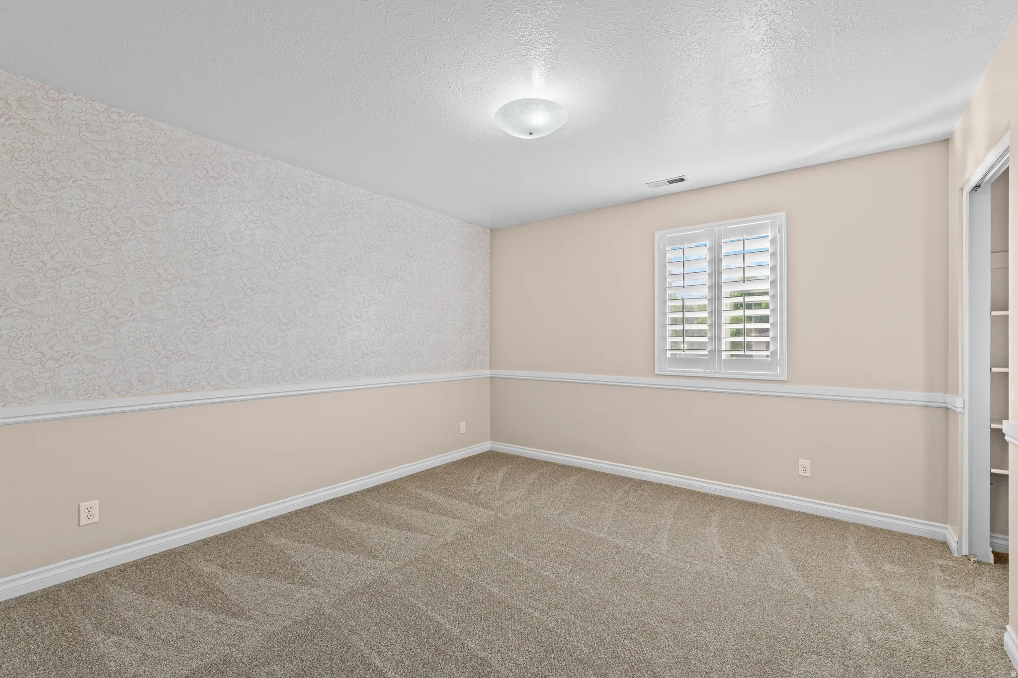 Interior room featuring neutral carpeting, a patterned accent wall, and white trim throughout