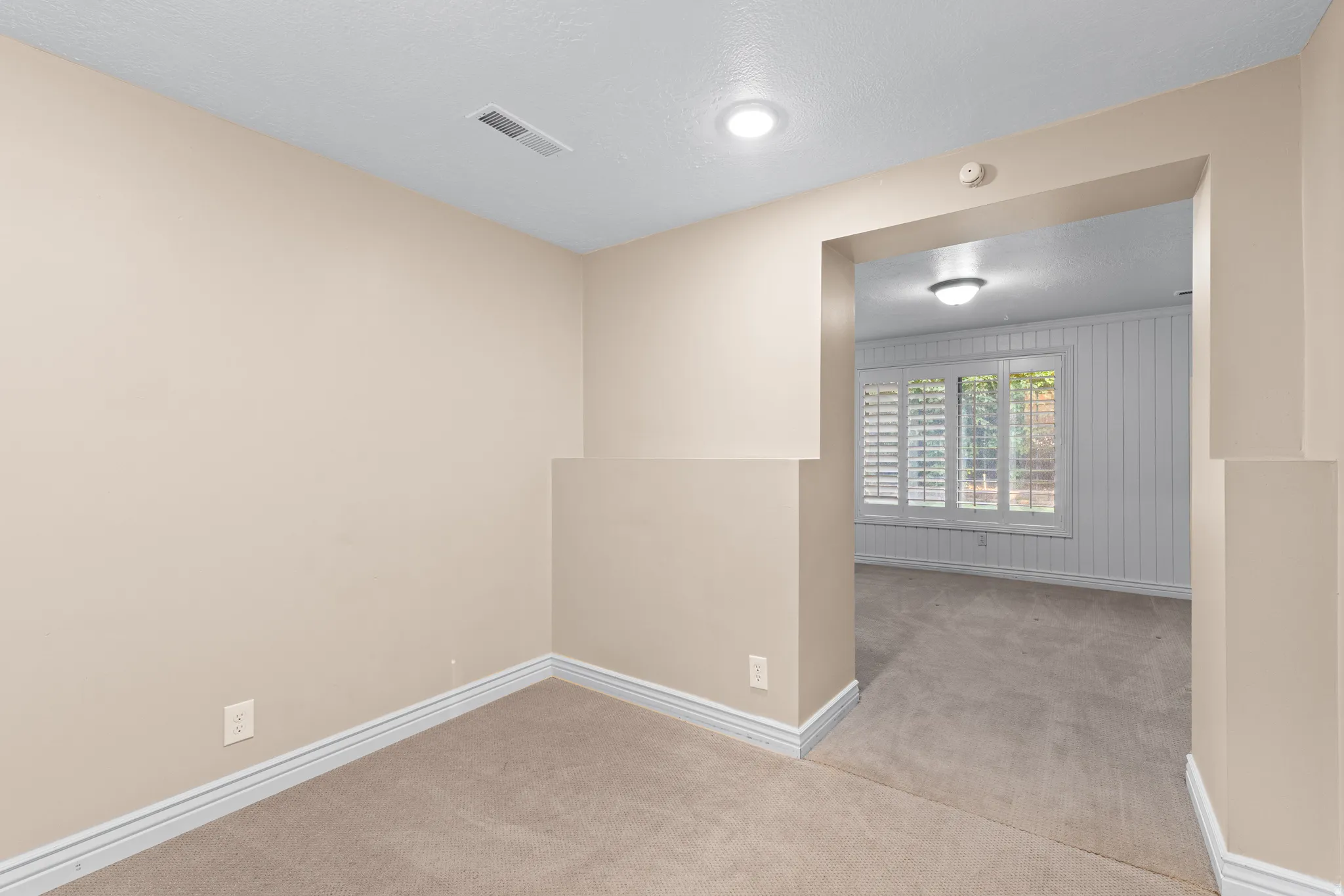 Carpeted interior space with neutral wall tones and white baseboards