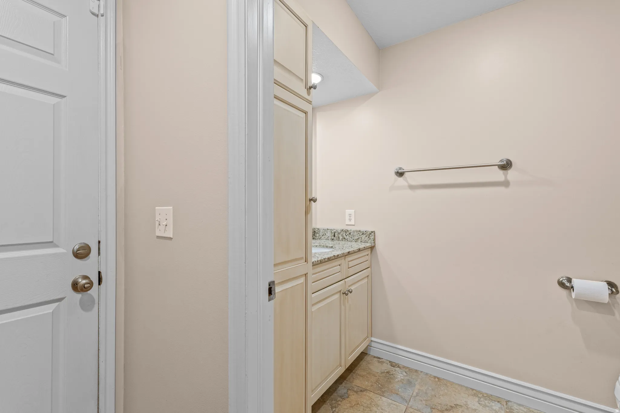 Vanity with granite countertop, integrated sink, and light wood cabinetry