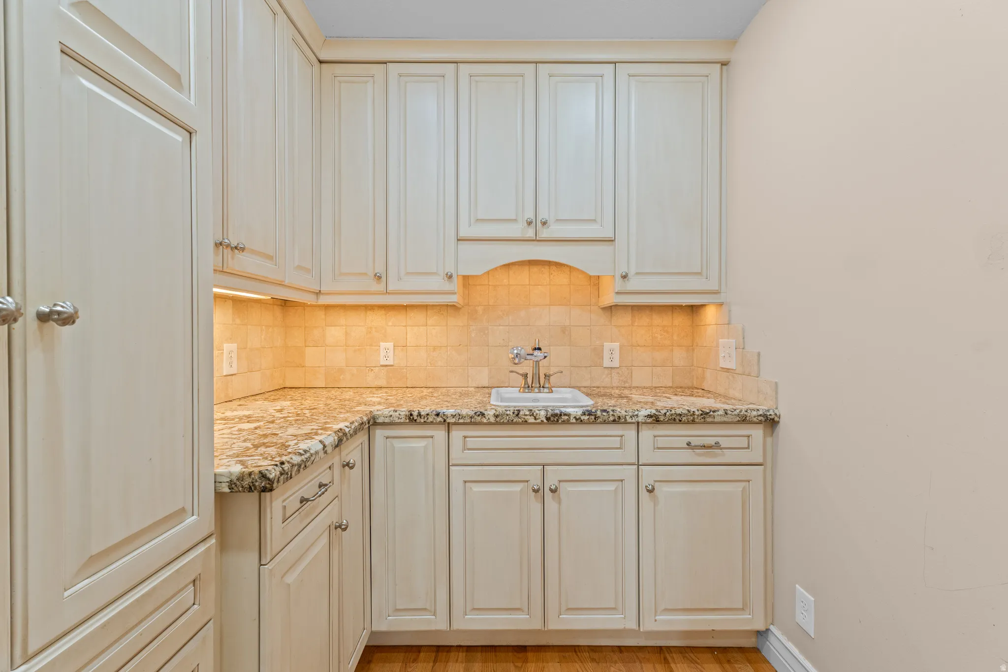 Built-in cabinetry with a light finish, granite-patterned countertops, and a tiled backsplash