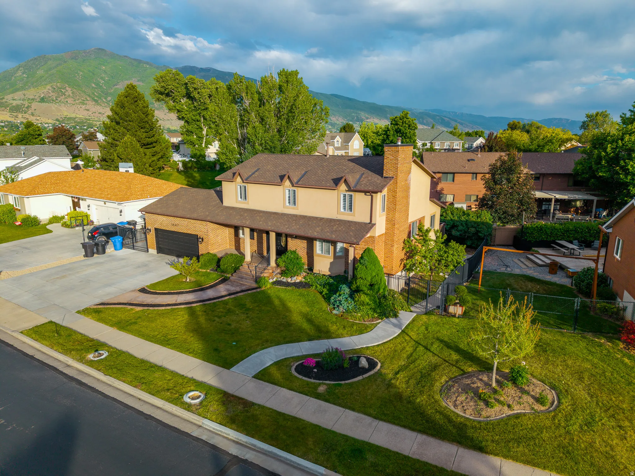 Two-story residence featuring a brick and stucco exterior, an attached garage, and a long driveway