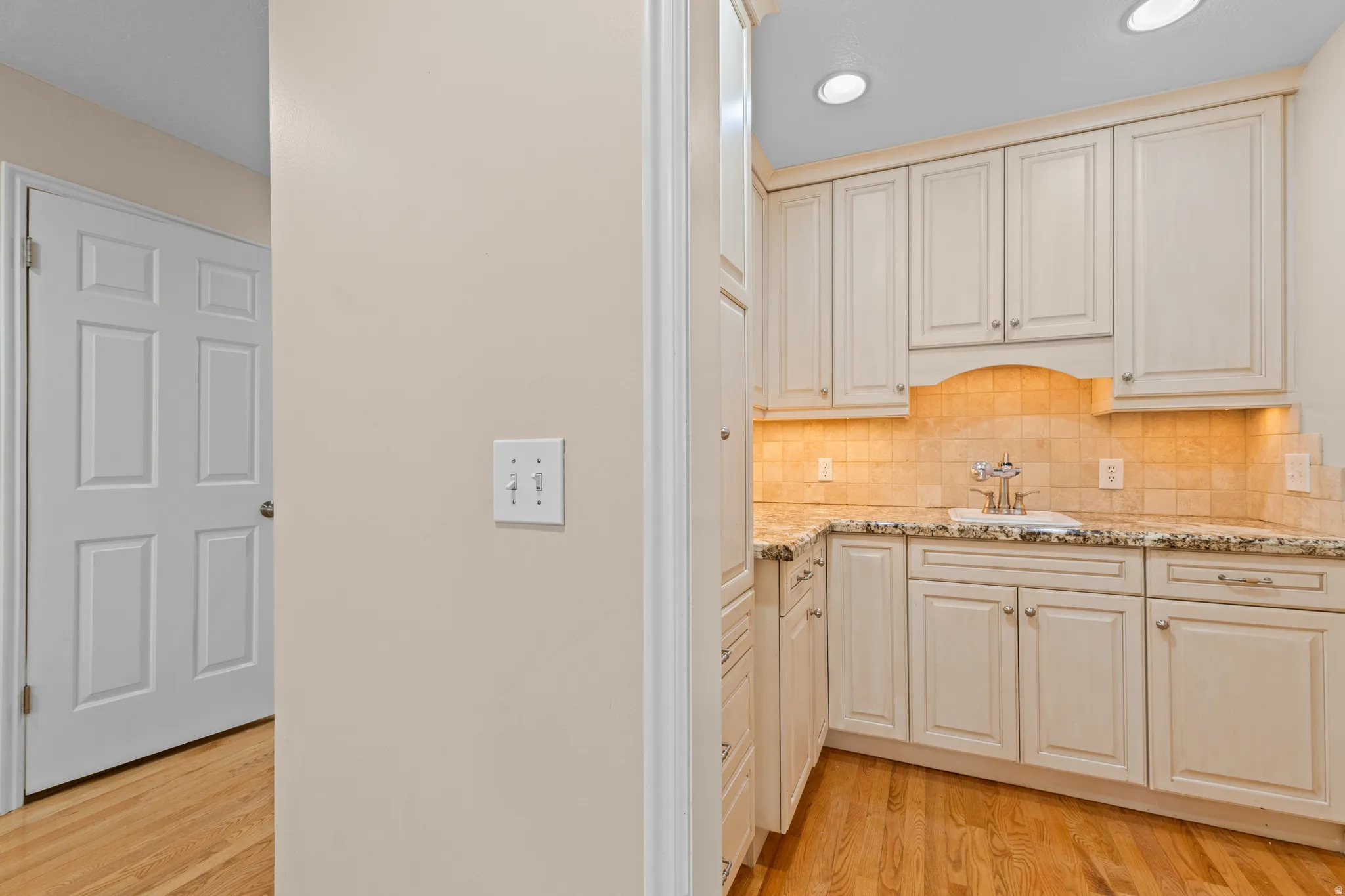 Built-in cabinetry with under-cabinet lighting, granite-look countertops, and a tile backsplash