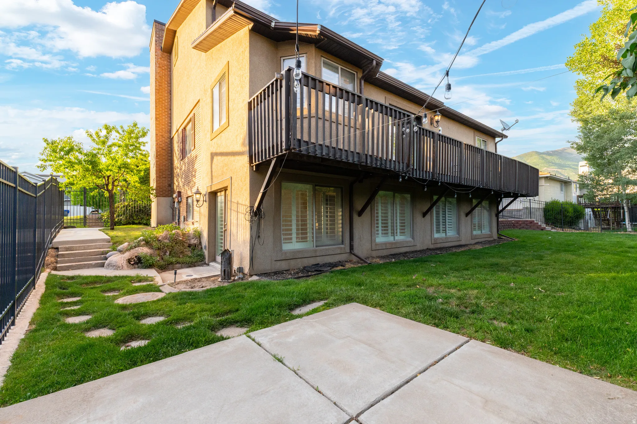 Rear exterior featuring a spacious wooden deck and a lower-level concrete patio